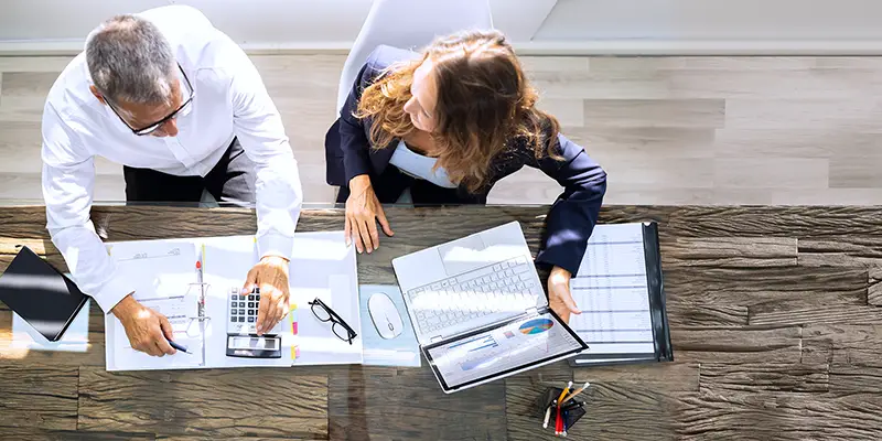 Manager And Senior Accountant Using Laptop In Office