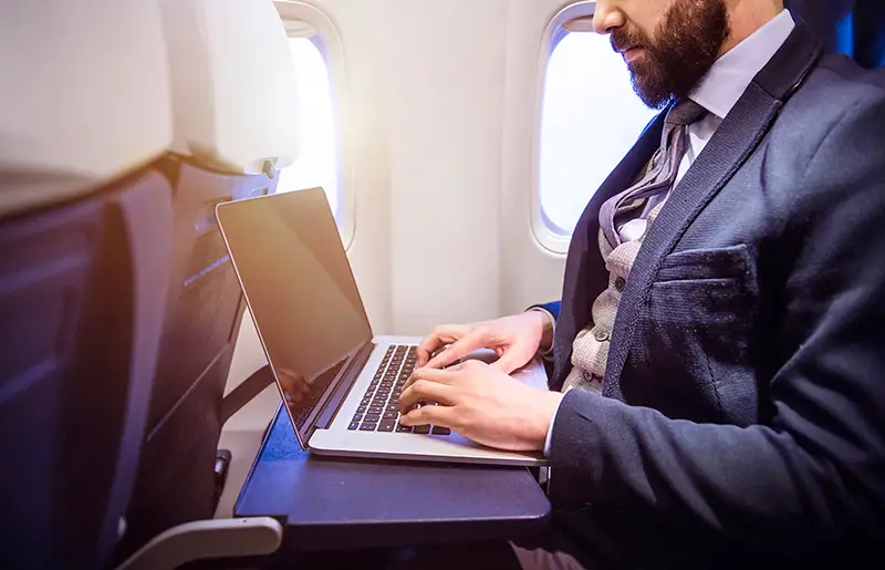 young businessman with notebook sitting inside an airplane