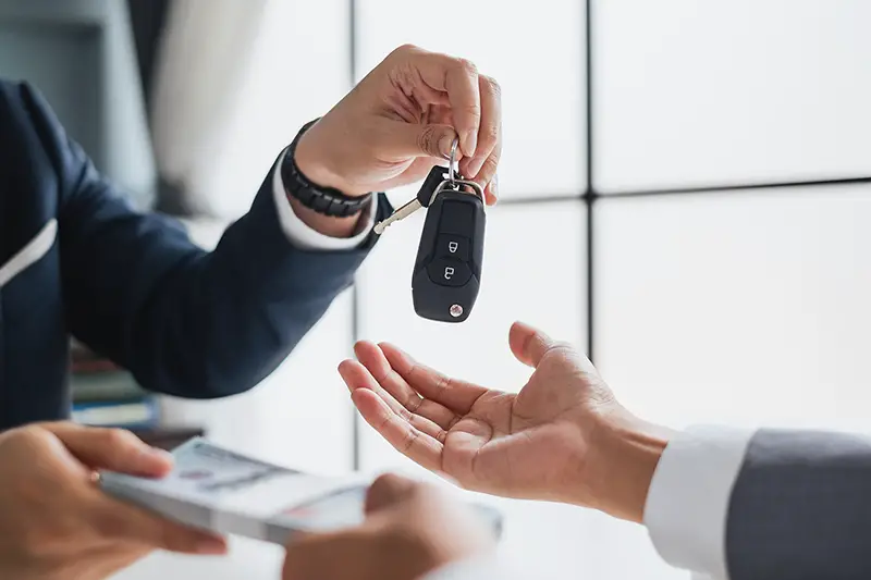 Closeup hand giving a car key and money for loan credit financial