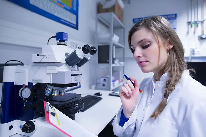 Female scientist reading notes on clipboard in lab