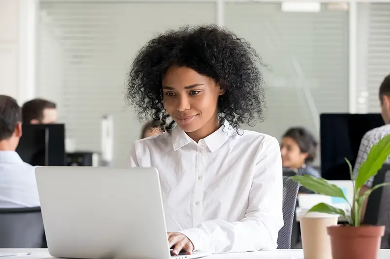 african female intern student worker working on laptop in modern office