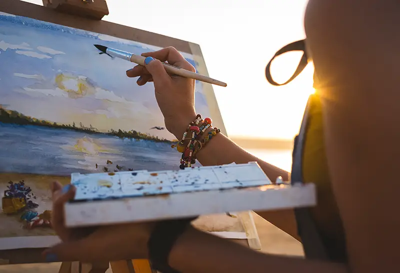 Young woman artist painting landscape