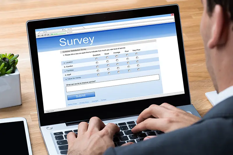 businessman giving online survey on laptop at office desk
