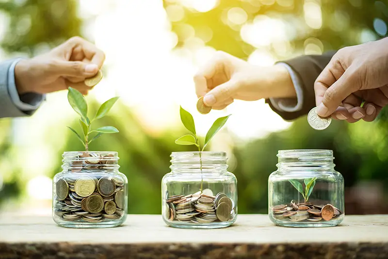 Businessman hands putting money (coin) into the glass jar