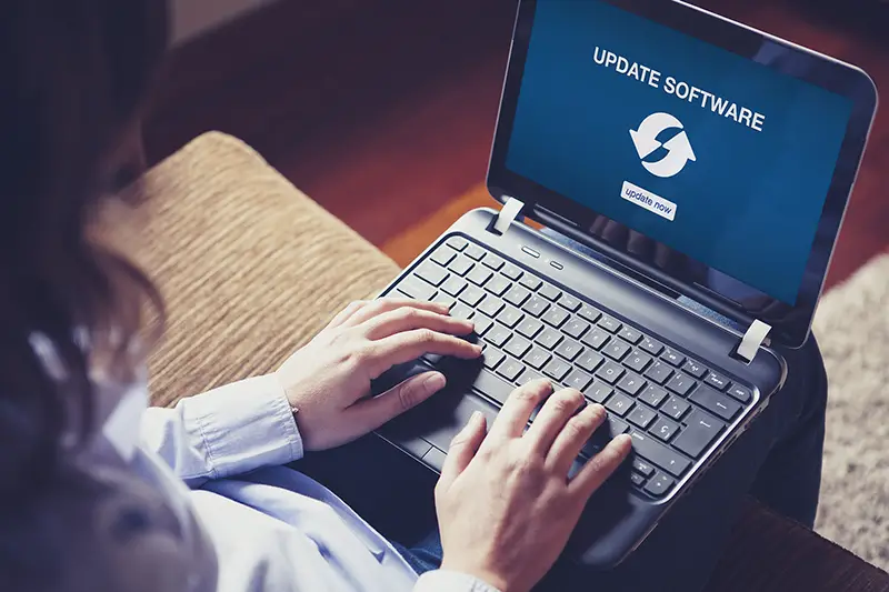 Woman updating laptop computer software sitting at home