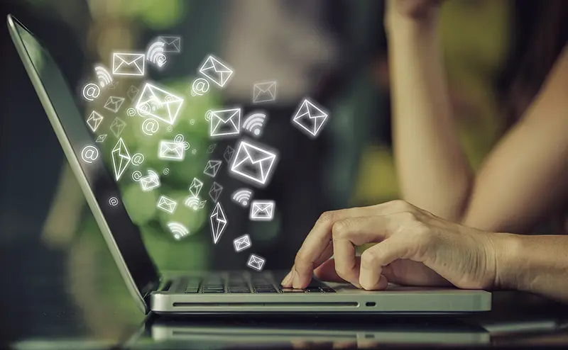 Person's hand using laptop with email icon