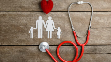 Red heart, stethoscope and paper chain family on wooden table