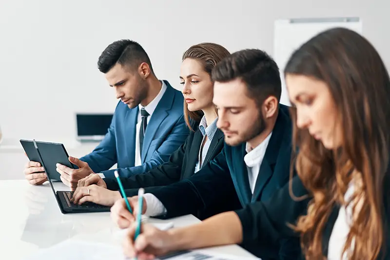 group of business people sitting in a row together at table