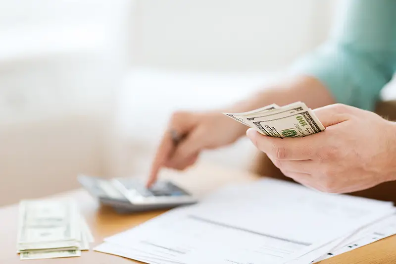 close up of man with calculator counting money