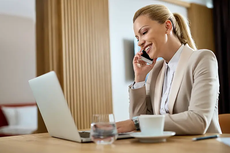 Happy businesswoman working on a computer and communicating over mobile phone