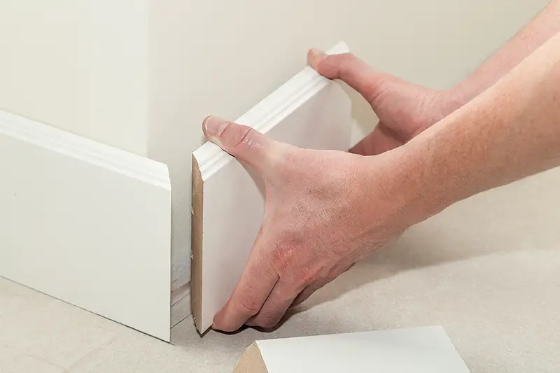 Man putting new skirting board in house