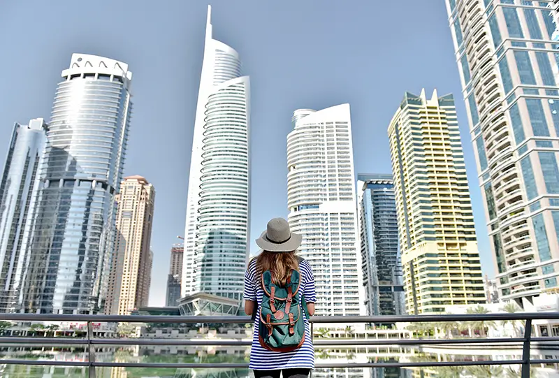 young traveler woman in big city Dubai in hat and travel bag