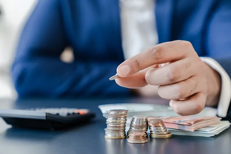 Businessman holding euro cents coins dollar bills on table