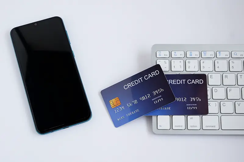 Credit card on computer keyboard with smartphone on white desk