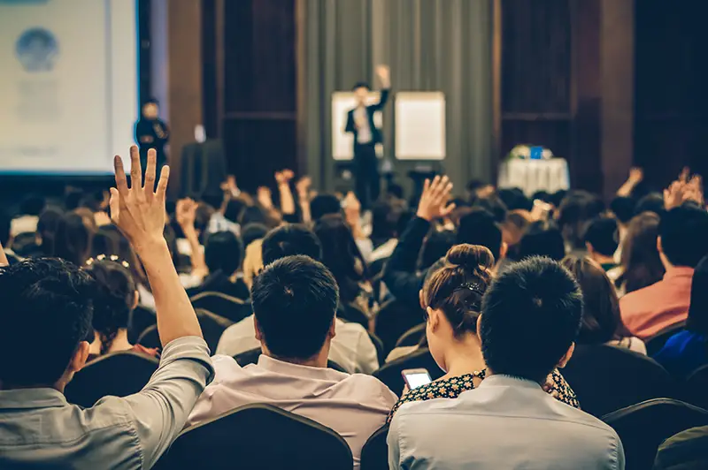 Speaker on the stage with Rear view of Audience in the conference hall