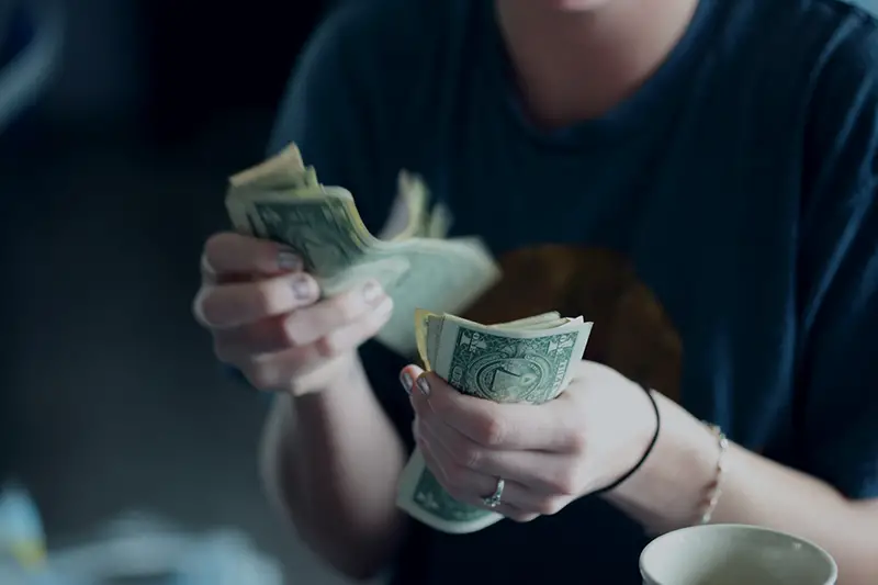 Person counting paper dollar bills