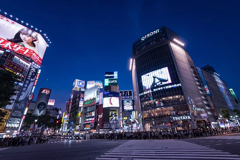 Pedestrians walk at Shibuya Crossing at dusk