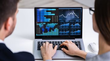Two Businesspeople Analyzing Financial Graph On Laptop