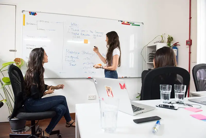 Young woman writing in front of big white board