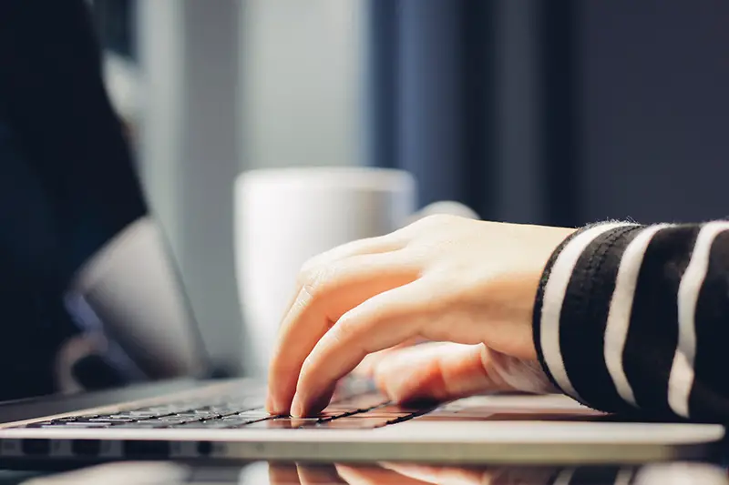 Female hands typing on keyboard of computer laptop