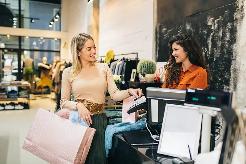 young blond woman paying her new clothes buyed in expensive boutique