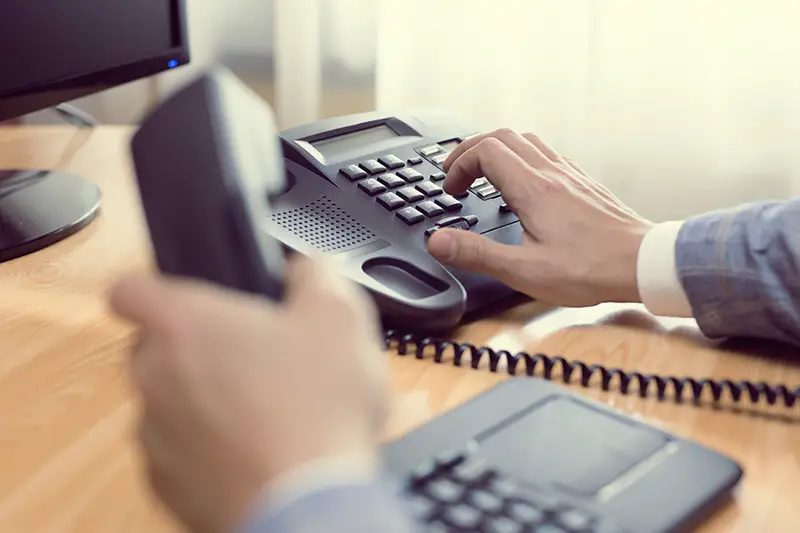 businessman dialing voip phone in the office