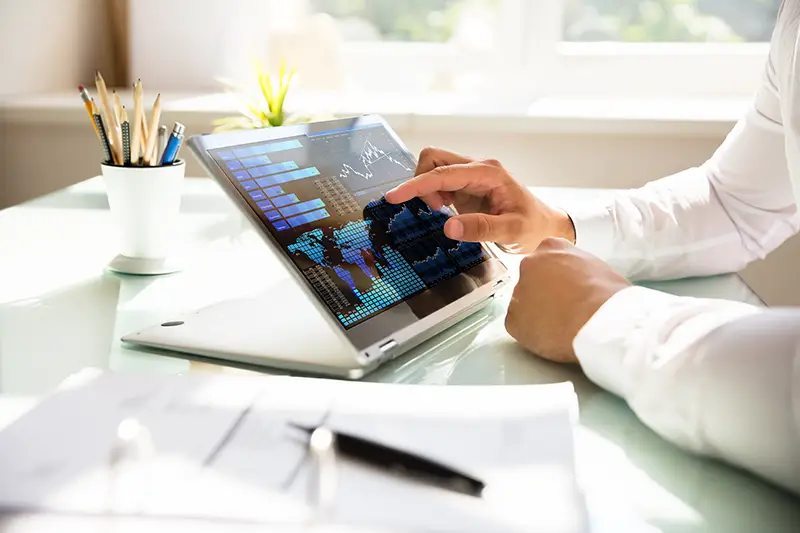 Close-up of a businessman's hand analyzing graph on laptop