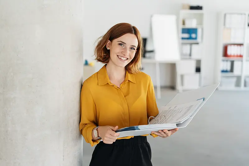 Attractive young office worker holding a large open binder