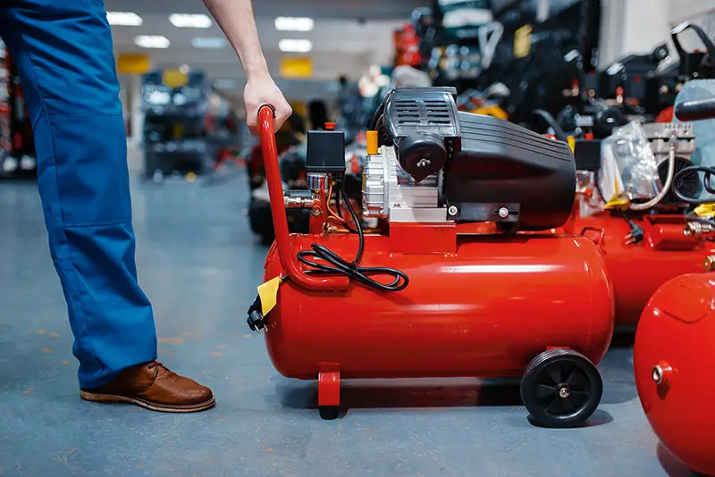 Worker choosing pneumatic compressor in tool store