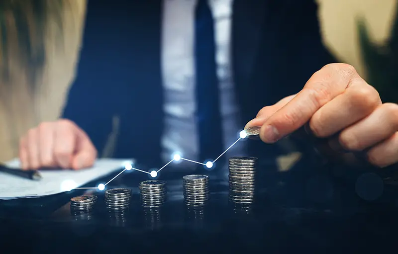 Businessman stacking coins with a graph of profit