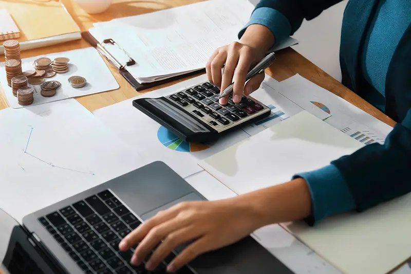 Woman accountant use calculator and computer on desk in office.