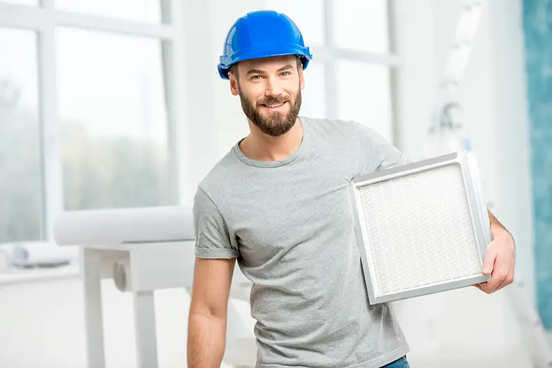 Worker holding air filter for installing in the house ventilation system