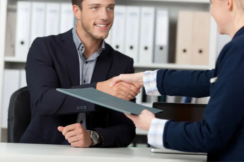 Young male applicant shaking hands with female interviewer in office