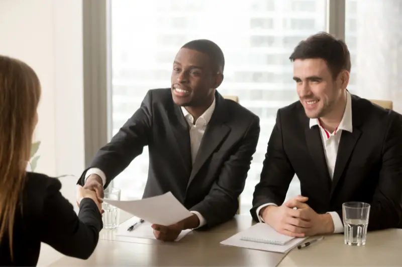 Two male recruiters welcoming a female applicant for a job interview