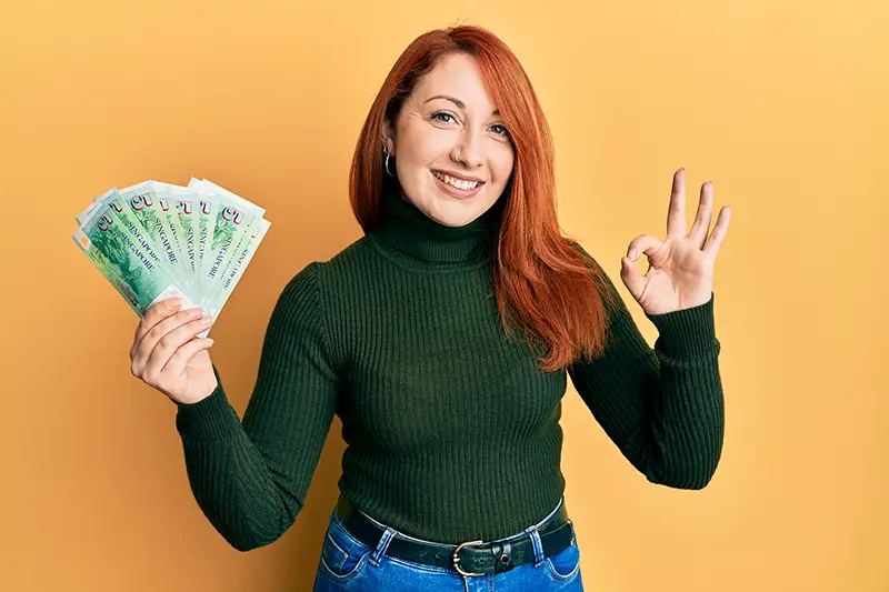 Woman smiling while holding Singaporean dollar bills