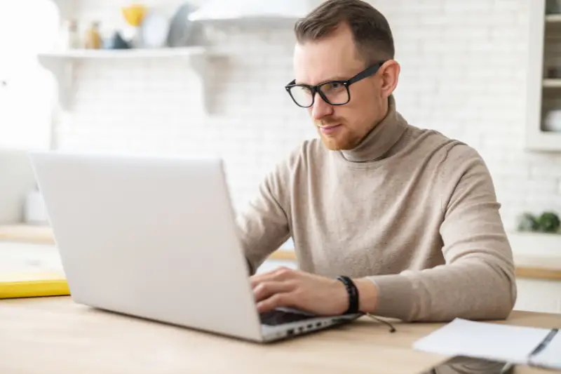 Man with eyeglasses focused working on his laptop computer