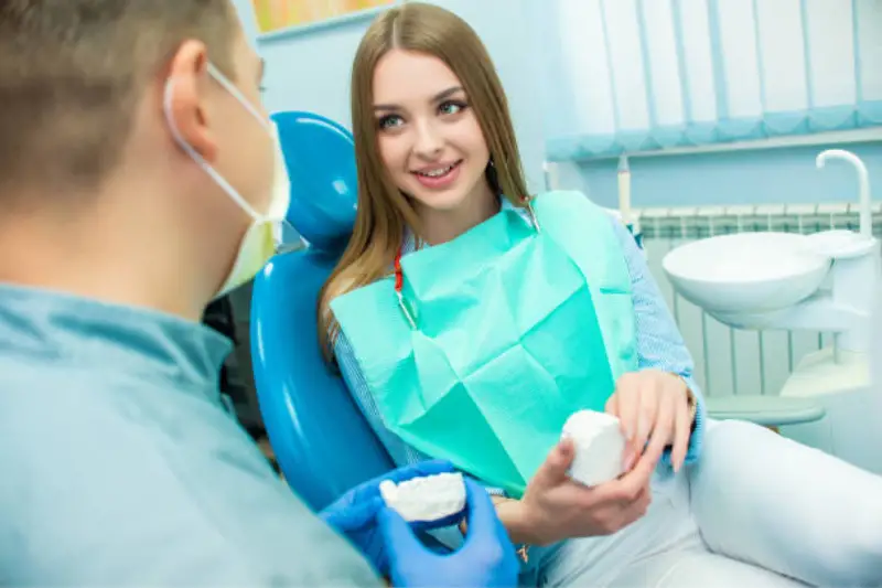 Young woman talking to the male dentist