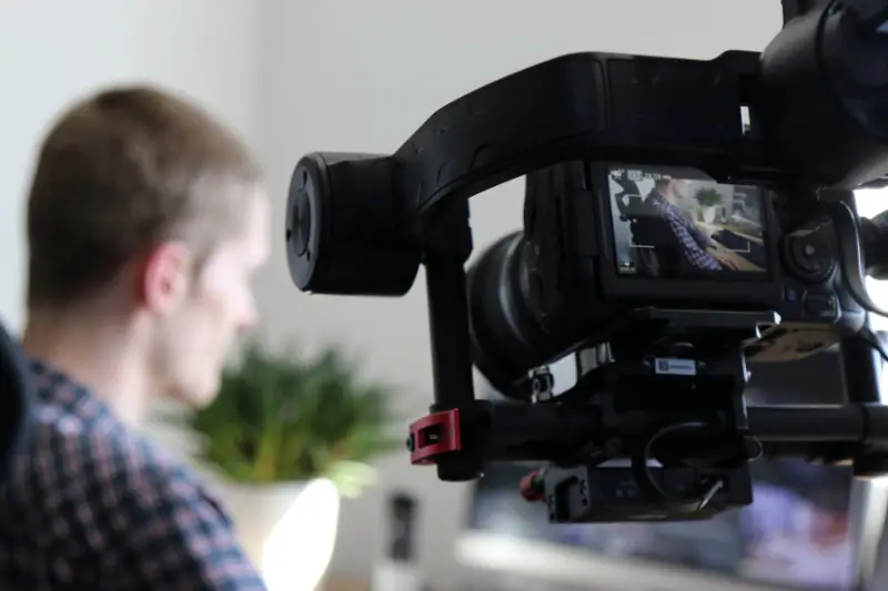 Black Video Camera Turn on Next to Man Wears Polo shirt