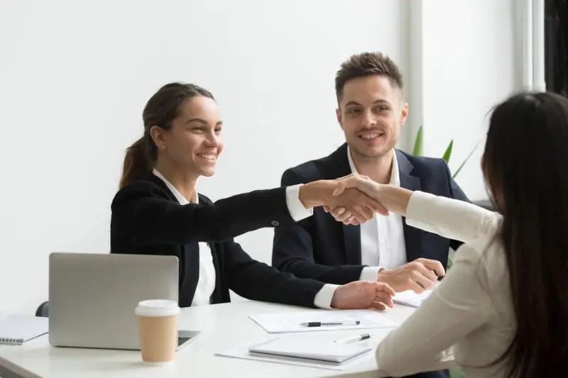 Smiling man and woman welcoming the female applicant for a job interview