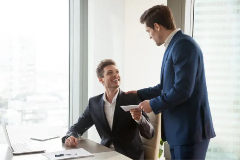 Manager presenting an envelope to a male employee