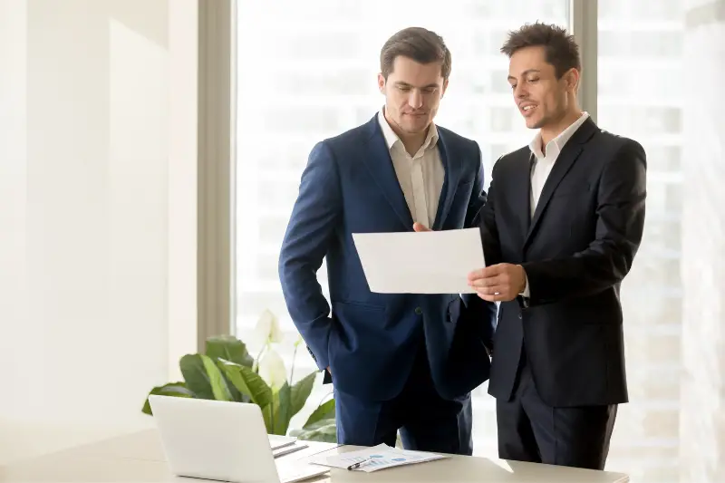 Two businessmen reading a document written on white paper