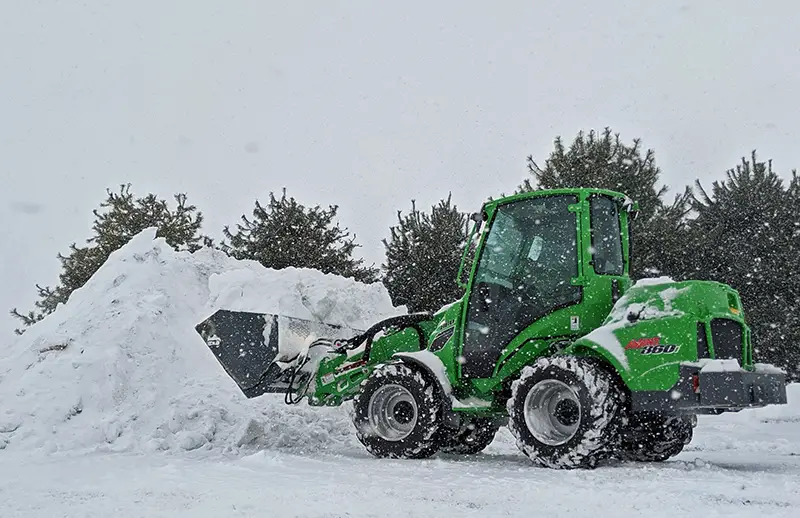 Avant 860 with large high-tip bucket moving a pile of snow