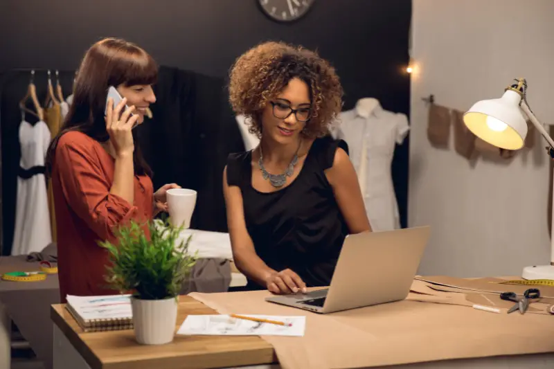 Businesswomen using laptop and smartphone inside the clothing store