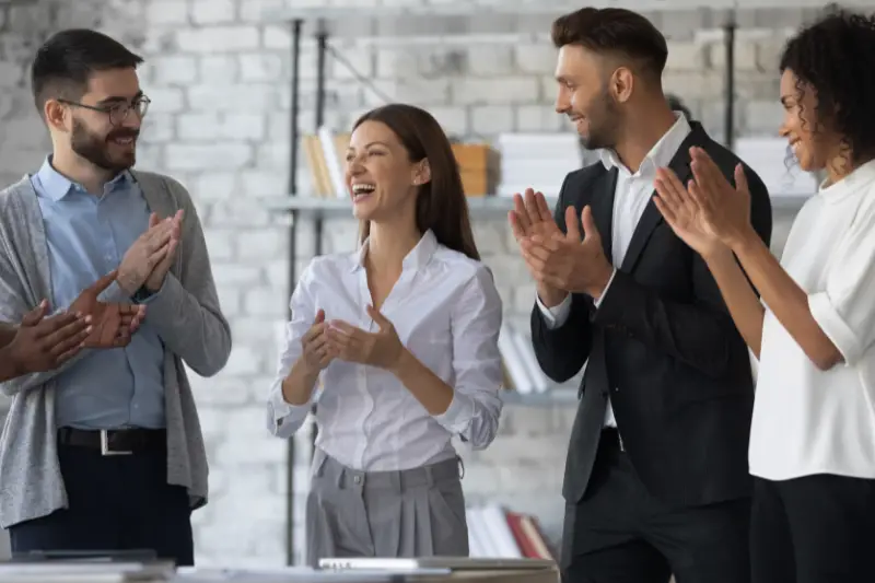 Friendly diverse employees congratulating businesswoman with achievement