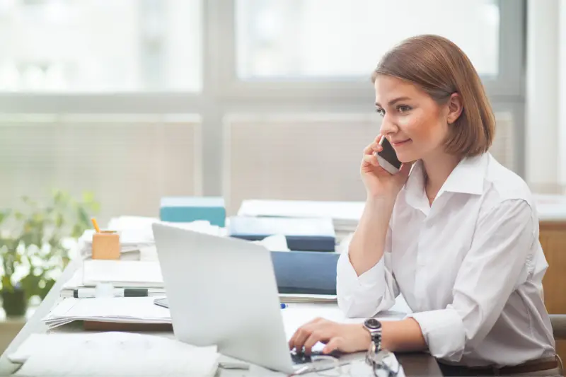 Young businesswoman working at the office and talking on the phone