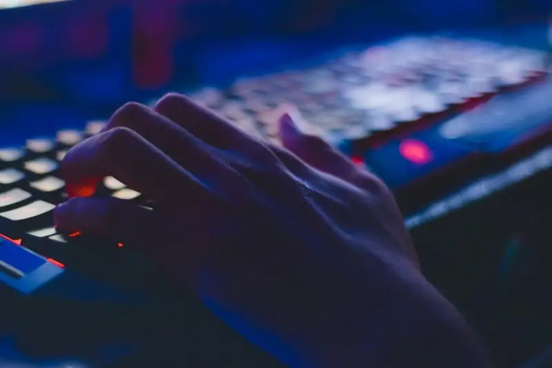 Person using laptop keyboard with lights on