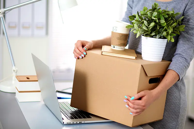 Woman carrying brown cardboard box for moving to the new office