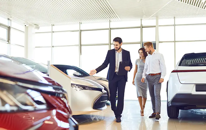 Couple and the dealer selling cars look the car in the showroom