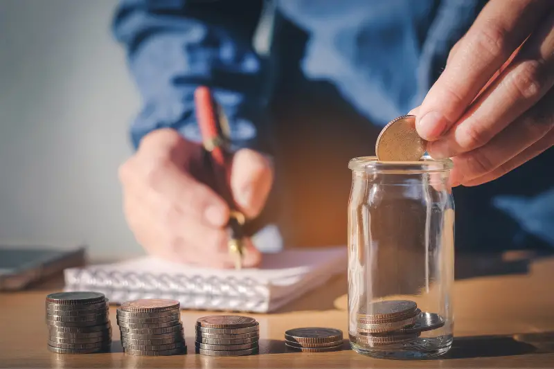 Person saving money on a glass jar