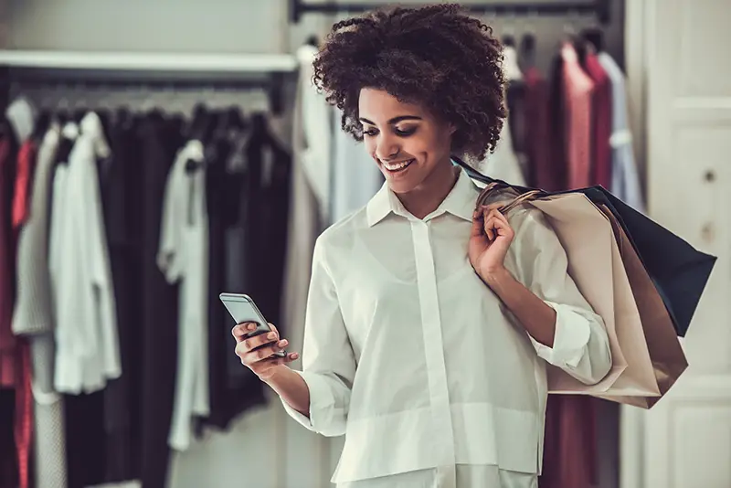 Young female customer holding her mobile phone while inside the retail store